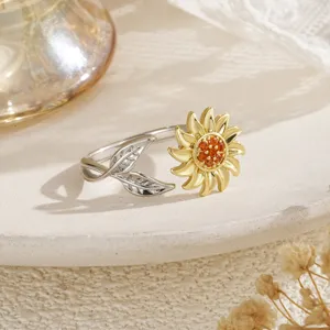 Vue détaillée d'une bague tournante tournesol bicolore avec pierres orange et feuilles.