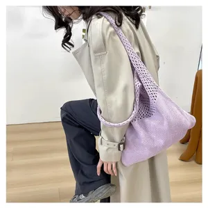 Primer plano de un bolso tote de punto violeta con textura de malla en una modelo.