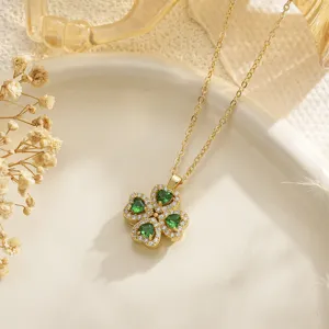 Macro detail of a rotatable green heart-shaped four-leaf clover necklace in gold finish.
