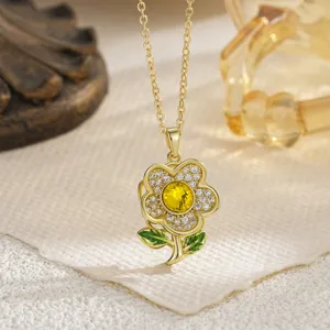 Close-up detail of a rotatable golden daisy necklace with yellow crystal and green leaves