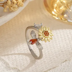 Détail exquis d'une bague ouverte bicolore avec motif de tournesol et abeille et pierres