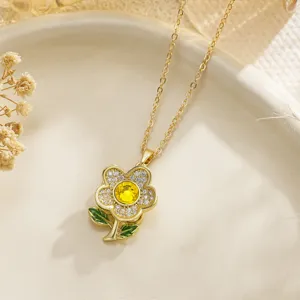 Close-up detail of a rotating gold daisy pendant with yellow center and green leaves