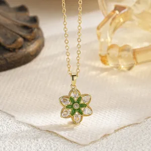 Close-up detail of a gold-plated flower pendant necklace featuring green and clear crystal stones
