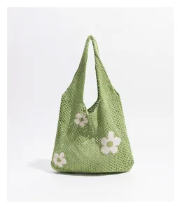 Primer plano de un bolso de malla tejida verde con motivos florales.
