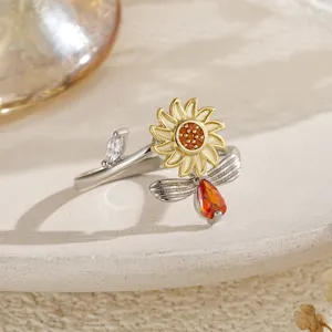 Gros plan d'une bague tournante tournesol et abeille avec cristaux orange et transparents.