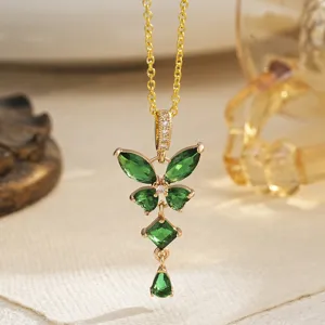 Macro view of a gold-plated necklace featuring an emerald green butterfly pendant.