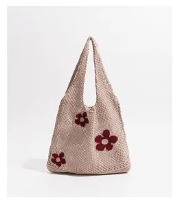 Vista detallada de la textura de punto calado y el motivo floral rojo en este bolso beige