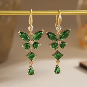 Detailed view of emerald green butterfly zircon earrings with gold finish and sparkling gems