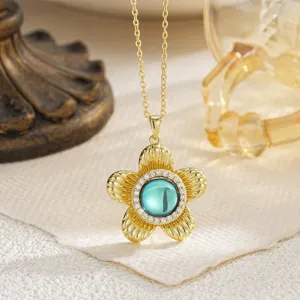 Primer plano de un collar con colgante de flor dorada, piedra cian y detalles de circón