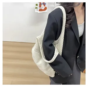 Modelo con un bolso tote blanco de punto calado con una elegante chaqueta negra
