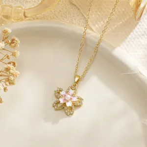 Macro view of an elegant gold cherry blossom necklace with pink enamel and clear zircons