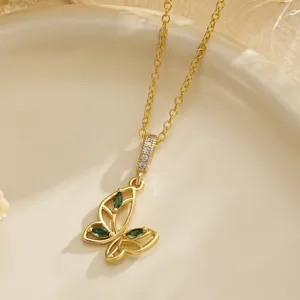 Detailed close-up of a vintage gold hollow butterfly pendant with emerald green zircons