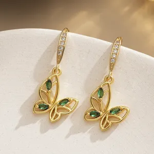 Detailed view of gold-plated butterfly earrings with emerald green and clear cubic zirconia