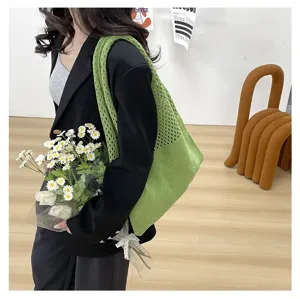 Bolso tote de punto verde combinado con blazer negro y margaritas para un look casual.