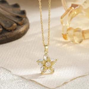 Close-up of gold flower pendant necklace with sparkling clear crystals and leaf detail.