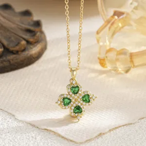 Detailed macro shot of an ornate golden four-leaf clover pendant with green heart-shaped gems