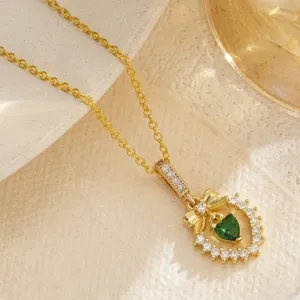 Macro view of retro gold-plated necklace with green heart zircon and bow detail