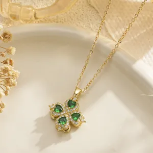 Close-up of a gold rotatable four-leaf clover pendant with green heart-shaped gems.