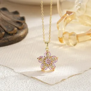 Detailed macro shot of a gold-plated flower pendant with pink and white gemstones.