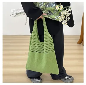 Primer plano de un bolso tote de punto verde con detalles calados y motivos de rombos.