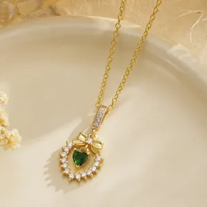 Detail of vintage gold plated necklace with emerald green heart zircon and bow pendant
