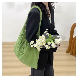 Primer plano del bolso tote de punto calado verde con un diseño literario y casual