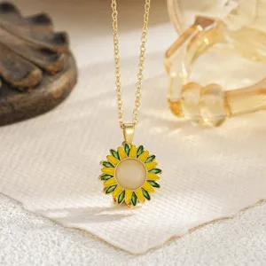 Close-up detail of a yellow sunflower pendant with green enamel petals on a gold chain
