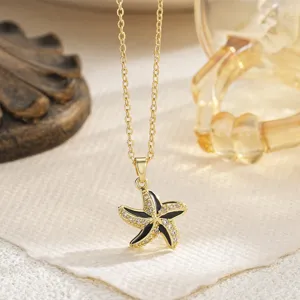 Close-up of gold starfish pendant with black enamel and zircons on a link chain