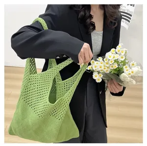 Bolso tote de punto calado verde hierba sostenuto por modelo con ramo de margaritas