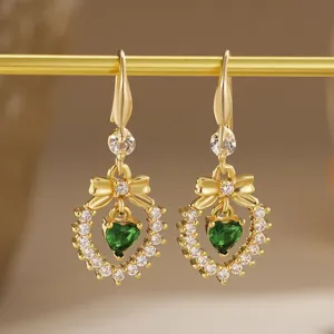 Close-up of vintage gold plated earrings with a heart-shaped green zircon stone