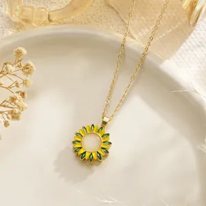 Close-up detail of a delicate yellow sunflower enamel pendant necklace on a gold chain.
