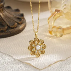 Macro detail of a rotatable gold flower pendant necklace with central pearl inlay.