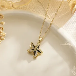 Detailed view of gold rotating starfish pendant with black enamel and sparkling zircons.