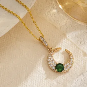 Detail shot of a retro gold-plated hollow crescent moon pendant with emerald green zircon