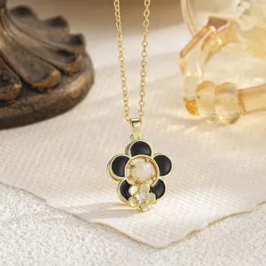 Close-up detail of a gold flower necklace with black petals and rotating zircon center.