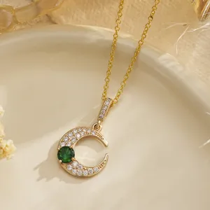 Detailed macro view of gold plated crescent moon necklace with sparkling green emerald zircon