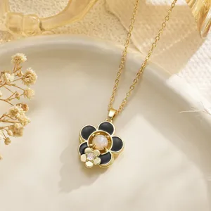 Detailed view of a gold flower necklace with rotatable black enamel camellia pendant
