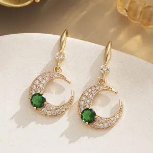 Macro view of vintage gold-plated crescent moon earrings with green and clear zircons