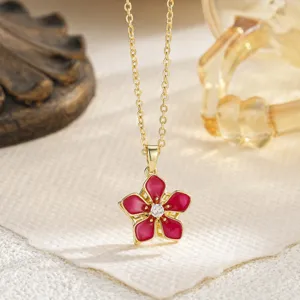 Macro detail of a rotating red enamel camellia flower pendant with a zircon center.