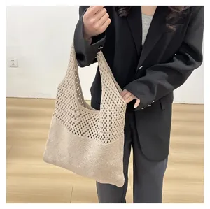 Primer plano de un bolso de punto beige sostenido por una modelo con una chaqueta negra.