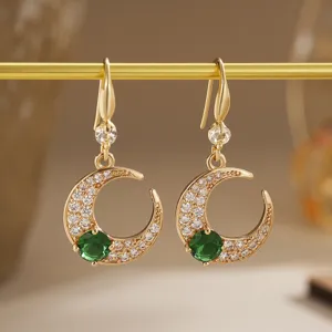 Detail view of crescent moon earrings featuring emerald green and white zircons.
