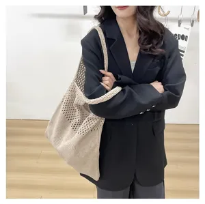 Bolso tote de punto calado beige combinado con una americana negra para un look chic.