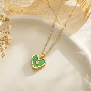 Close-up of green enamel heart pendant necklace with cubic zirconia on white plate