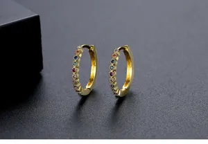 Detailansicht eleganter goldener Creolen besetzt mit kleinen bunten Zirkonsteinen