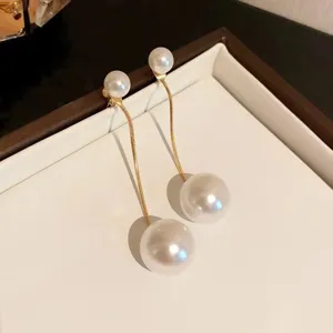 Macro view of elegant pearl tassel drop earrings featuring gold-tone thin chains