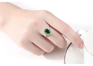 Vista detallada de un elegante anillo de plata con una gran piedra preciosa verde en el dedo.