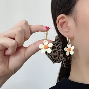Detaillierte Nahaufnahme kleiner frischer Gänseblümchen-Ohrringe mit weißen Blütenblättern.