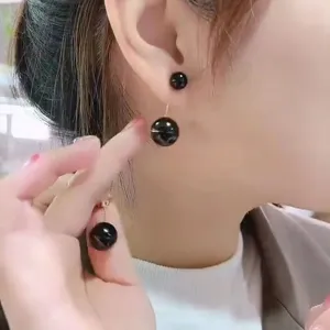 Detailed macro shot of elegant black double-sphere tassel earrings on a model's ear