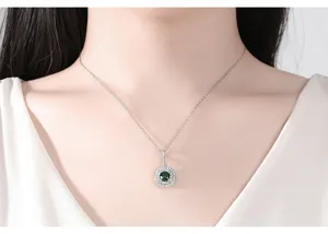 Detalle de elegante colgante halo de plata con circonita verde en cuello de modelo