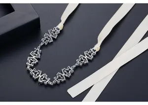 Primo piano di una collana da sposa con zirconi lucenti e un elegante nastro di raso crema